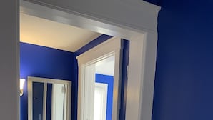 A hallway with blue walls, a white door, and a mirror. - Royalty Homes - College Style 3 bedroom Apartment (Baltimore)
