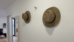 Un pasillo con una pared blanca, una puerta y dos sombreros colgados en la pared.