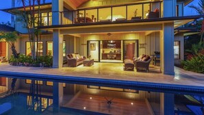 Une maison moderne à deux étages dotée d’une piscine, d’un espace extérieur aménagé et d’une grande salle à manger.