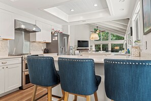 A modern kitchen with white cabinetry, stainless steel appliances, and a large island with bar stools.