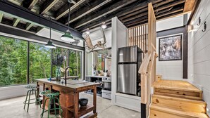A modern kitchen with a large island, stainless steel appliances, and a wooden staircase. - Your own pool! Sauna, Theater, Top 1% (Gatlinburg)