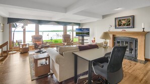 A spacious living room with a fireplace, a television, and a view of a lake. - Sandy Shore Beach House:  Lake Minnetonka (Mound)