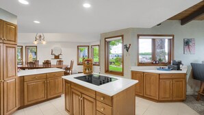 A spacious kitchen with wooden cabinets, a central island, and large windows offering views of the outdoors. - Sandy Shore Beach House:  Lake Minnetonka (Mound)