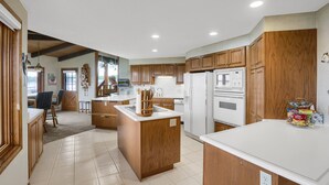 A modern kitchen with wooden cabinets, white countertops, and a central island. - Sandy Shore Beach House:  Lake Minnetonka (Mound)