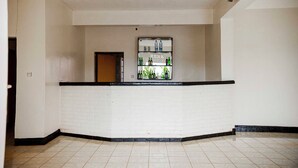 Um lobby limpo e vazio com uma parede de tijolos brancos, uma vitrine de vidro emoldurada a preto com garrafas e chão em azulejos.