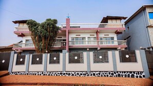 Um edifício residencial de vários andares com varandas, entrada com portão e base de pedra.