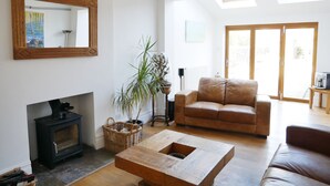A spacious living room with a fireplace, a leather sofa, a wooden coffee table, and a large mirror on the wall. - Close to beaches and town (Broadstairs)
