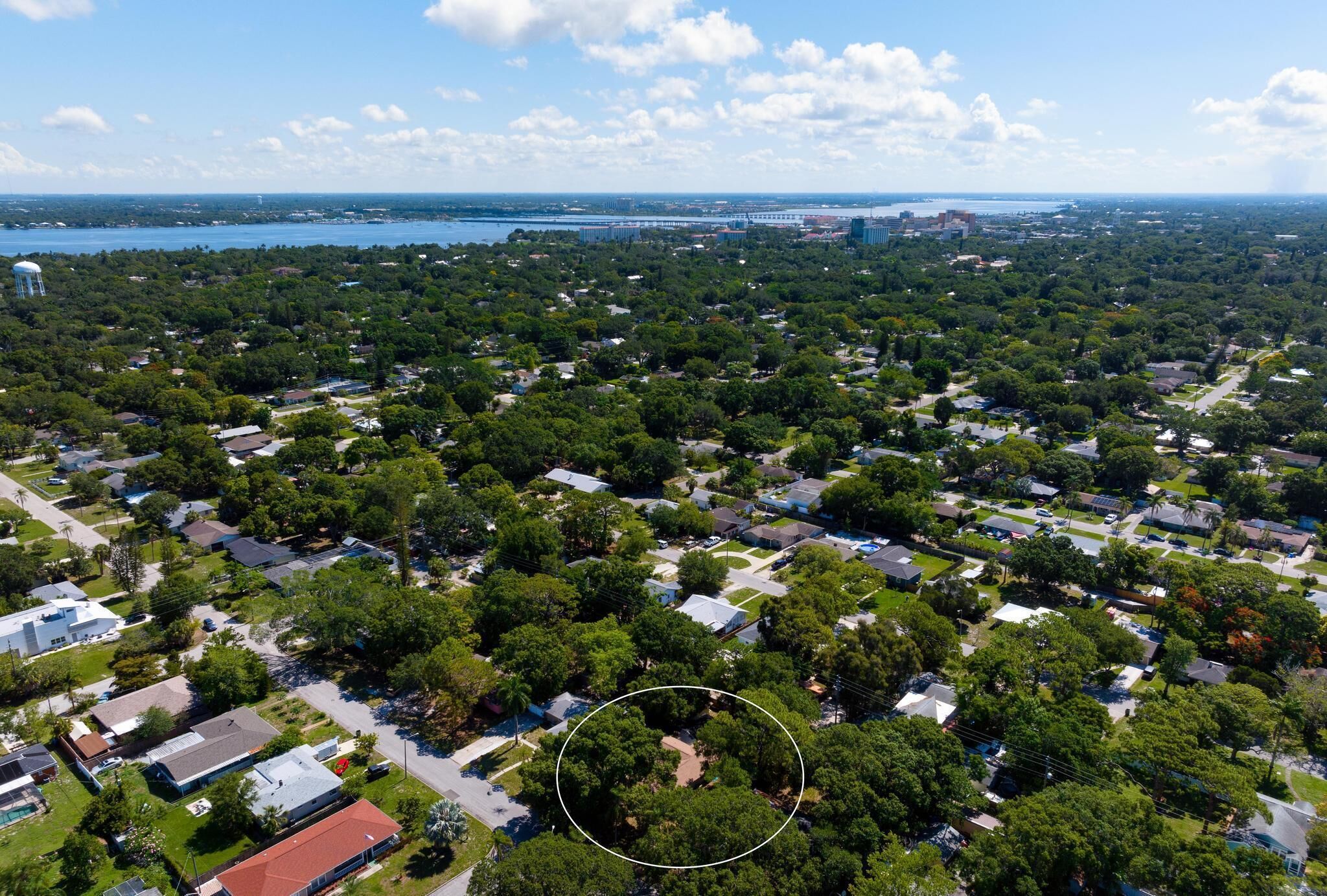 Vista aérea de una zona residencial con casas, árboles y una masa de agua al fondo.