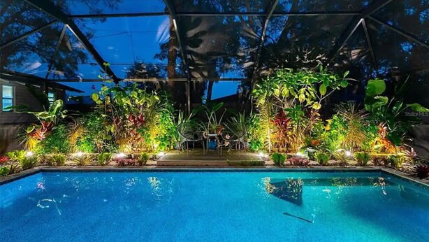 A swimming pool with a surrounding garden and a covered area with a metal roof. - Backyard Oasis & Resort Style Pool (Bradenton)