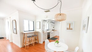 A modern kitchen with white cabinets, a dining area with a round table and white chairs, and a wooden floor. - Backyard Oasis & Resort Style Pool (Bradenton)