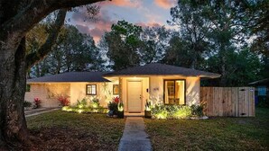 A single-story house with a front door, a small porch, and a wooden fence in the background. - Backyard Oasis & Resort Style Pool (Bradenton)