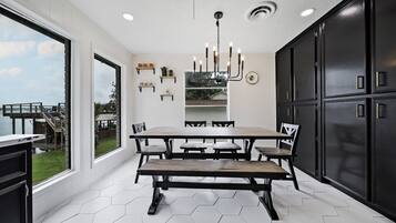 Une cuisine moderne dotée d’une grande table à manger, de meubles de rangement noirs et offrant une vue sur l’extérieur.