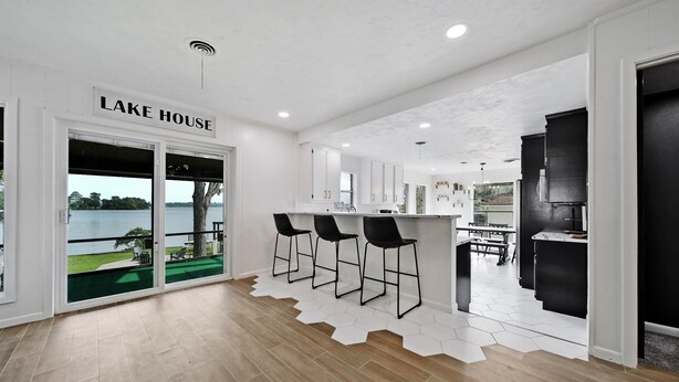 A modern kitchen with a bar area, a dining area, and a view of a lake.