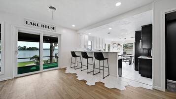 Une cuisine moderne avec un coin bar, un espace repas et une vue sur un lac.
