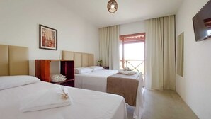 Een hotelkamer met twee bedden, een houten garderobe, een schilderij aan de muur en een raam met gordijnen.