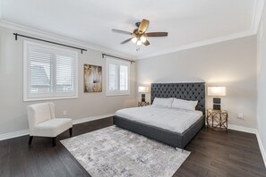 A bedroom with a large bed, a chair, a ceiling fan, and two bedside tables with lamps. - Waterfront Ellite Villa (Milton)