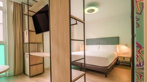 Une chambre avec un lit superposé, un bureau avec une télévision et une table de chevet.