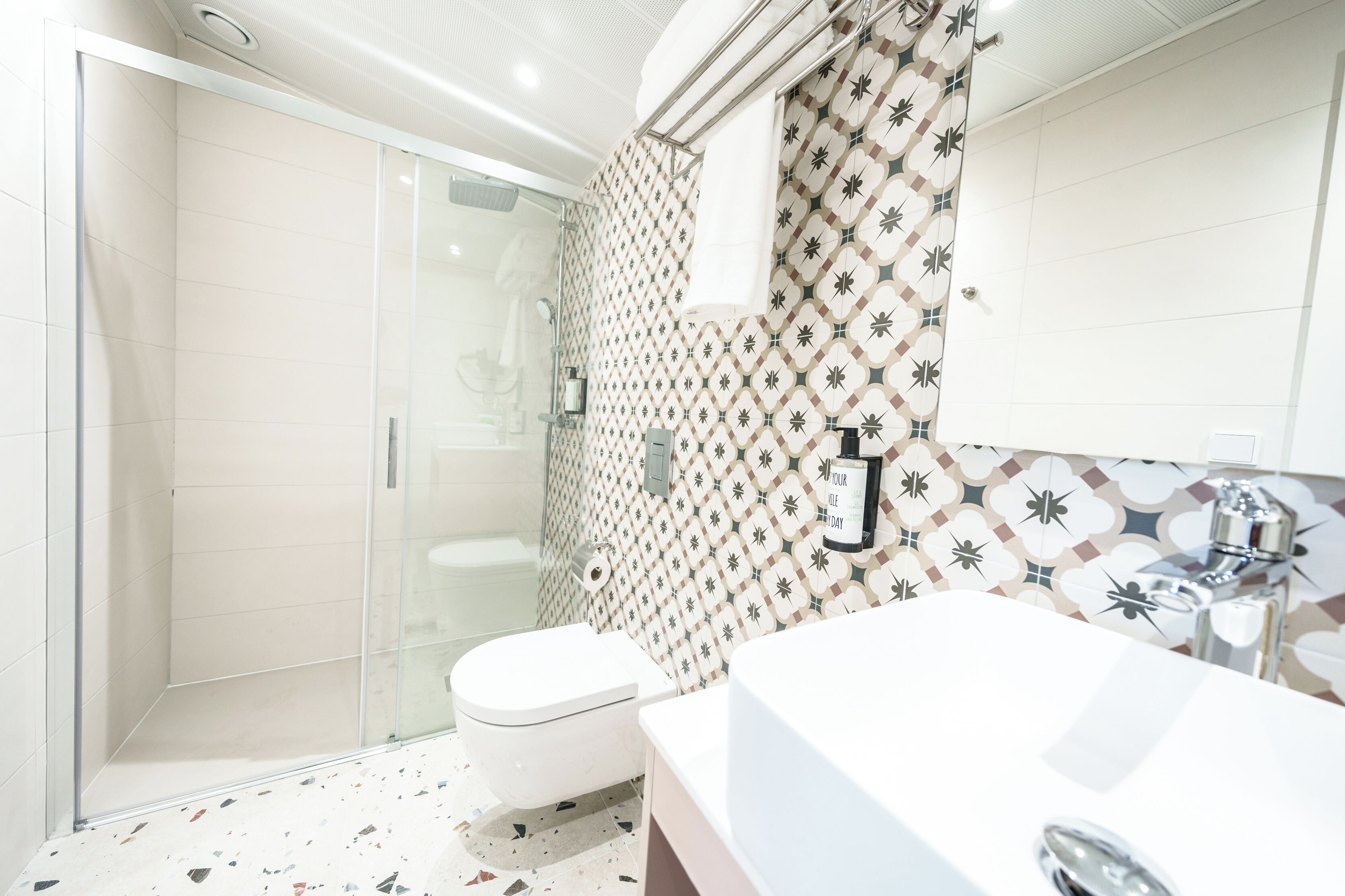 Un baño moderno con cabina de ducha de vidrio, inodoro y lavamanos con espejo.