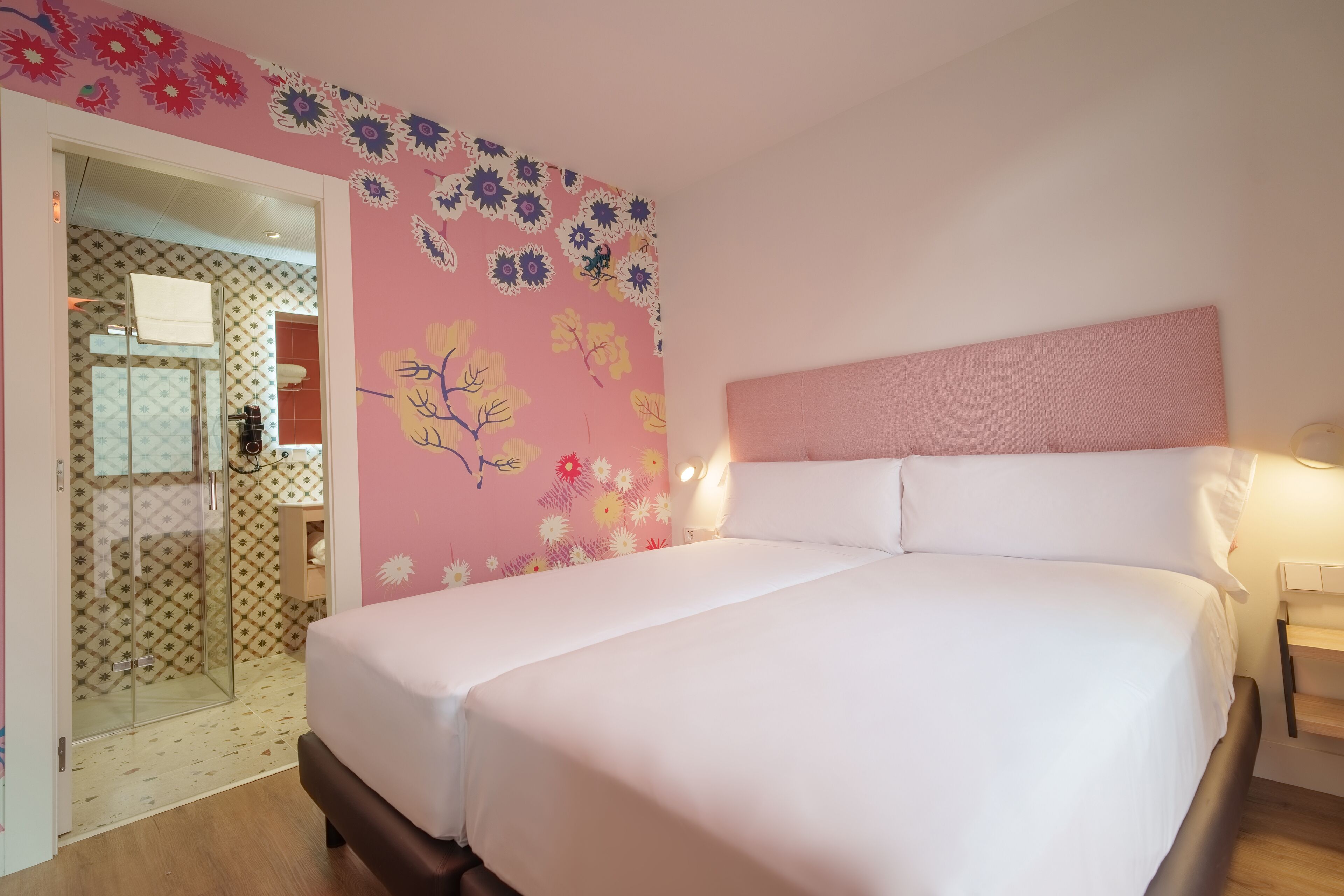 Een slaapkamer met een bed, een hoofdbord en een wand met bloemenbehang.