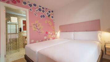 Un dormitorio con cama, cabecera y pared con papel tapiz floral.