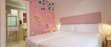 A bedroom with a bed, a headboard, and a wall with floral wallpaper.