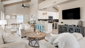 A spacious living room with a high ceiling, a kitchen area, and a dining space. - Beach Bliss | Epic Views, Games & Pets! (Crystal Beach)