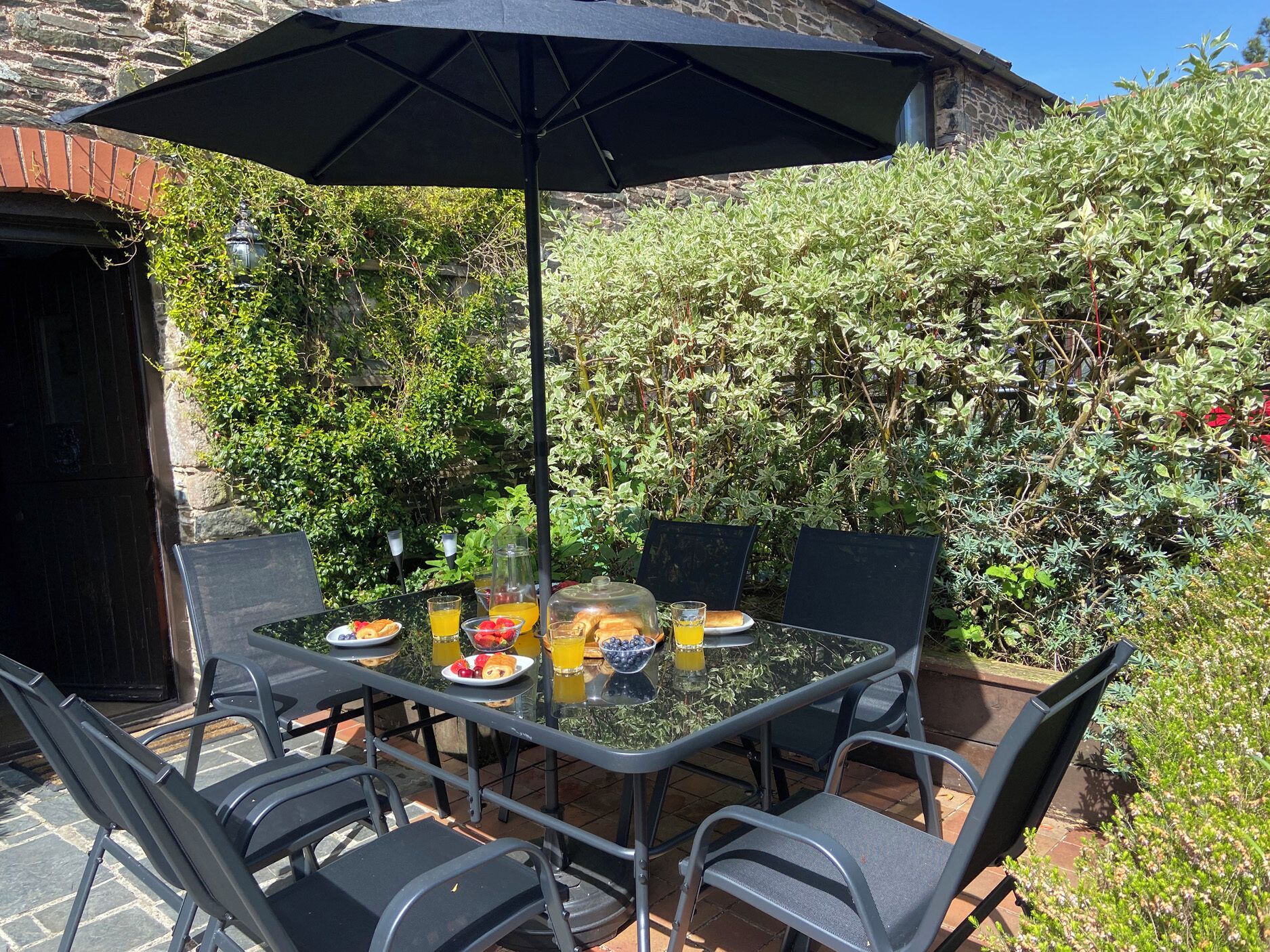 An outdoor dining area with a table, chairs, and an umbrella.