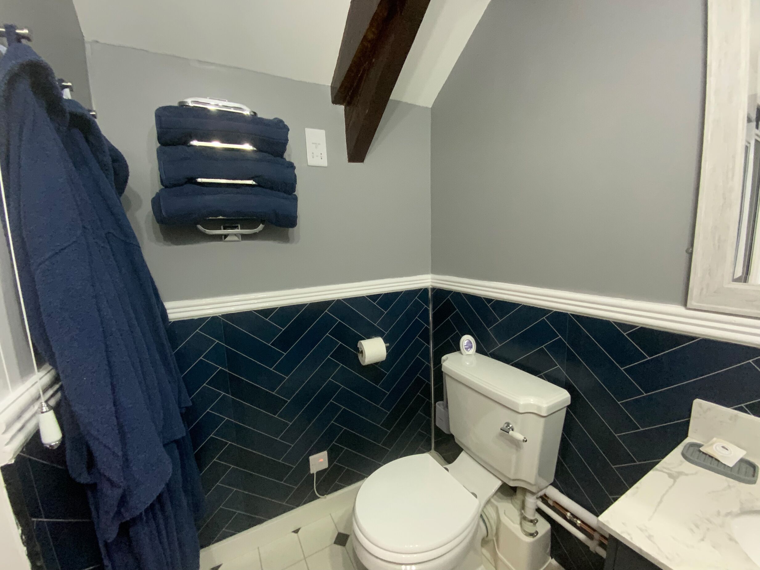 Une salle de bain avec des toilettes, un porte-serviettes avec des serviettes et un sol carrelé.