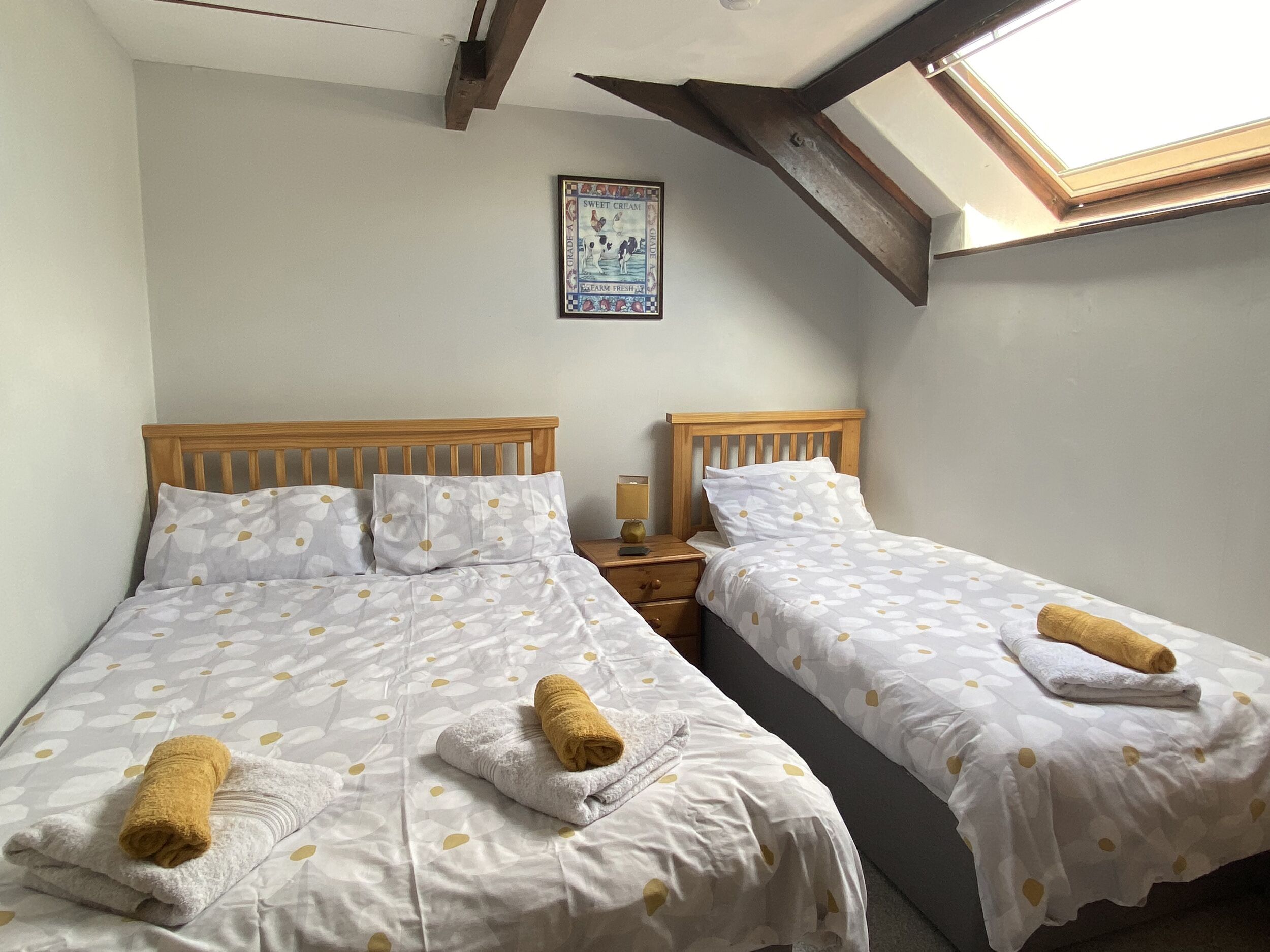 Ein Schlafzimmer mit zwei Einzelbetten, jeweils mit weißer Bettdecke und Handtuch.