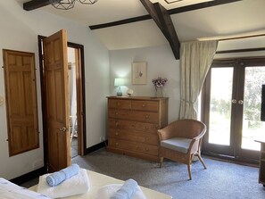 Quarto com cama, cômoda, cadeira e janela com cortinas.