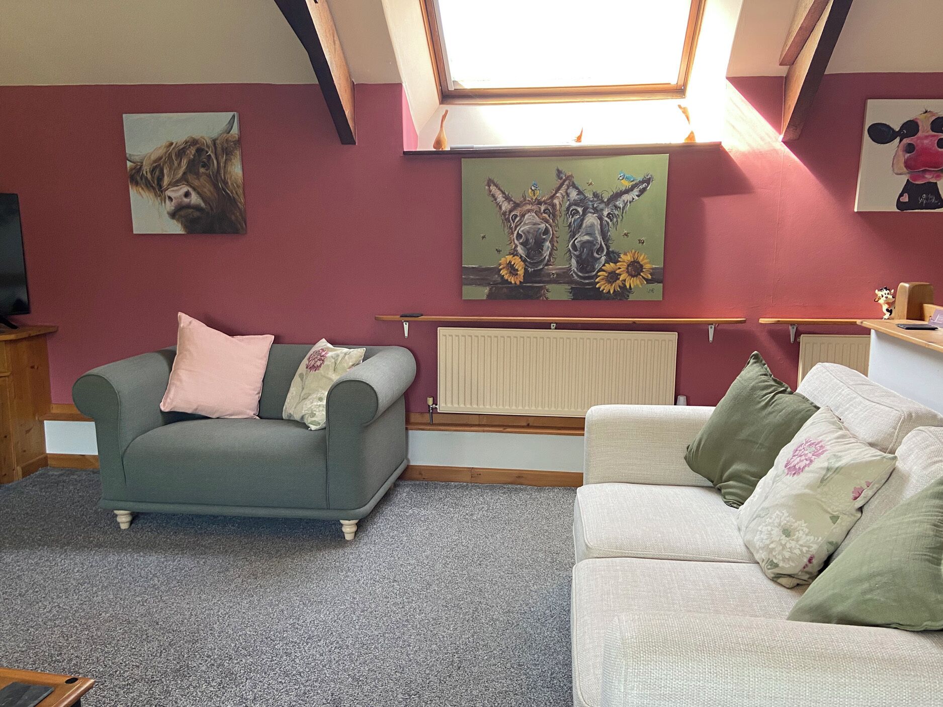 Een woonkamer met twee banken, een radiator en kunstwerken aan de muur.