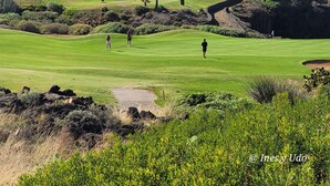 Camp de golf amb vista a l'oceà i a les muntanyes al fons.
