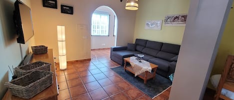Ein Wohnzimmer mit einer Couch, einem Couchtisch, einem Fernseher und einer Lampe.