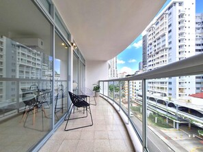 Enjoy a panoramic view of the city from the balcony with a seating area and large windows offering a view of neighboring high-rise buildings.