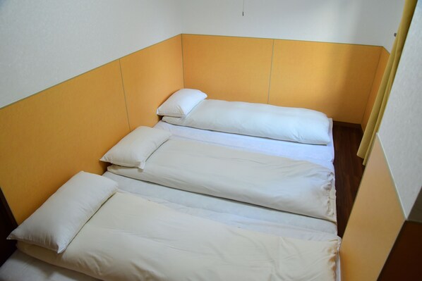 A single bed with white bedding in a room with yellow walls and a wooden floor. - Ueno House VIP (Tokyo)