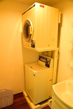 A compact laundry room with a front-loading washer and dryer stacked vertically. - Ueno House VIP (Tokyo)