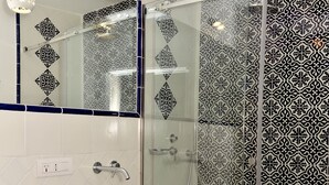 Une salle de bain moderne avec un lavabo blanc, une douche en verre et des carreaux à motifs.