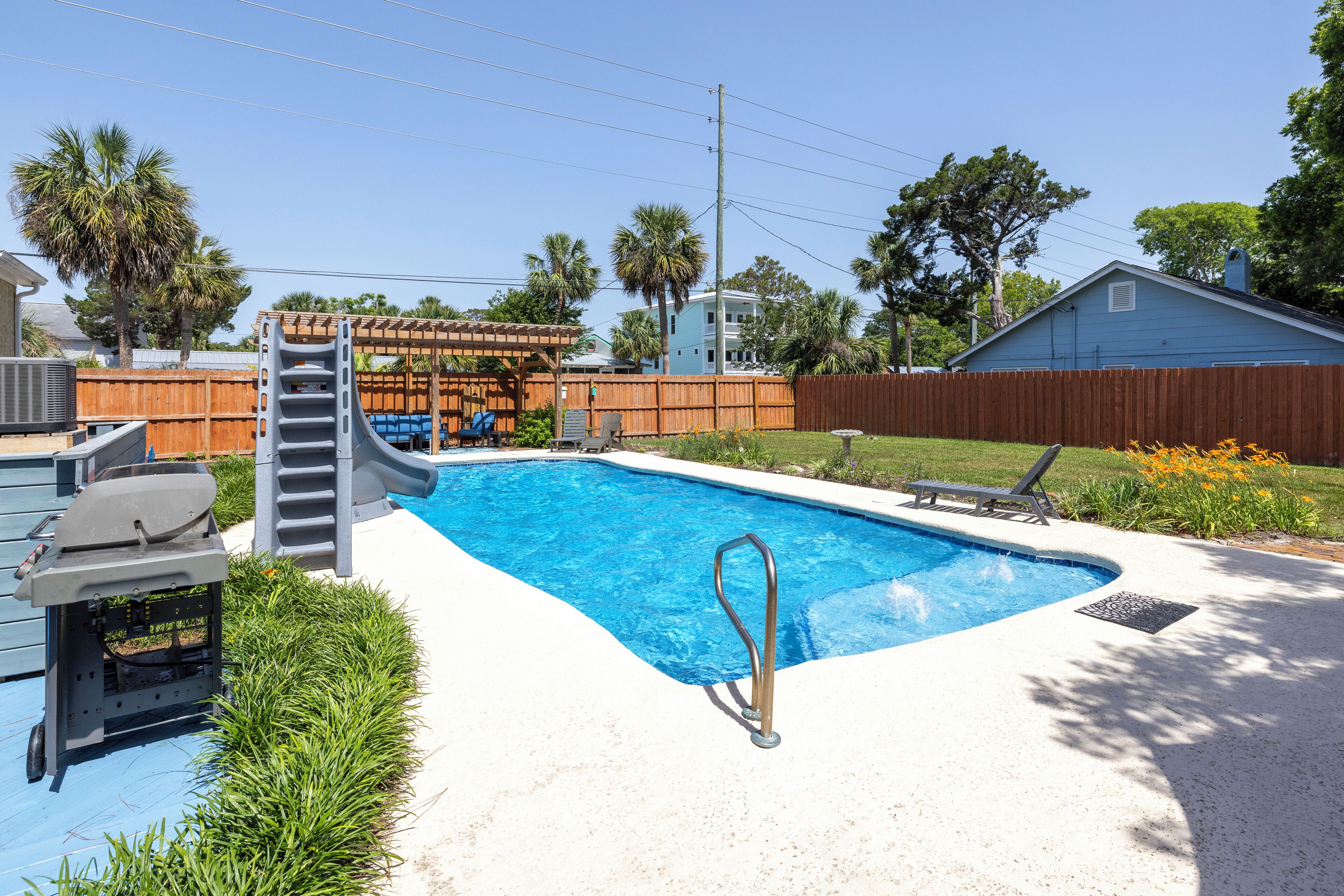 Un patio trasero con piscina, terraza de madera y zona de patio techada.