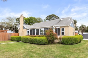 A two-story house with a chimney, a covered porch, and a well-maintained lawn.