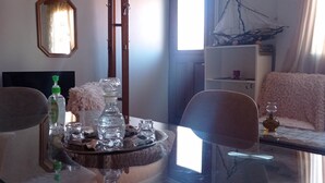 Quarto com mesa de jantar posta com copos e garrafas, espelho na parede e janela com cortinas.