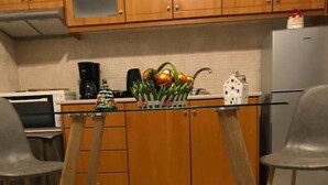 Uma cozinha com armários de madeira, uma geladeira, uma cafeteira e uma árvore de Natal decorativa no balcão.