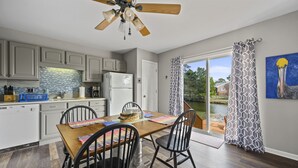 A modern kitchen with grey cabinets, a wooden dining table, and a ceiling fan.