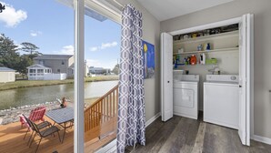 A room with a view of a canal, a wooden deck with chairs, and a laundry area with two washing machines.