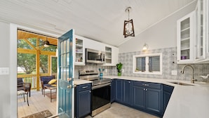 Una cucina moderna con mobili blu scuro, ripiani bianchi e forno integrato.