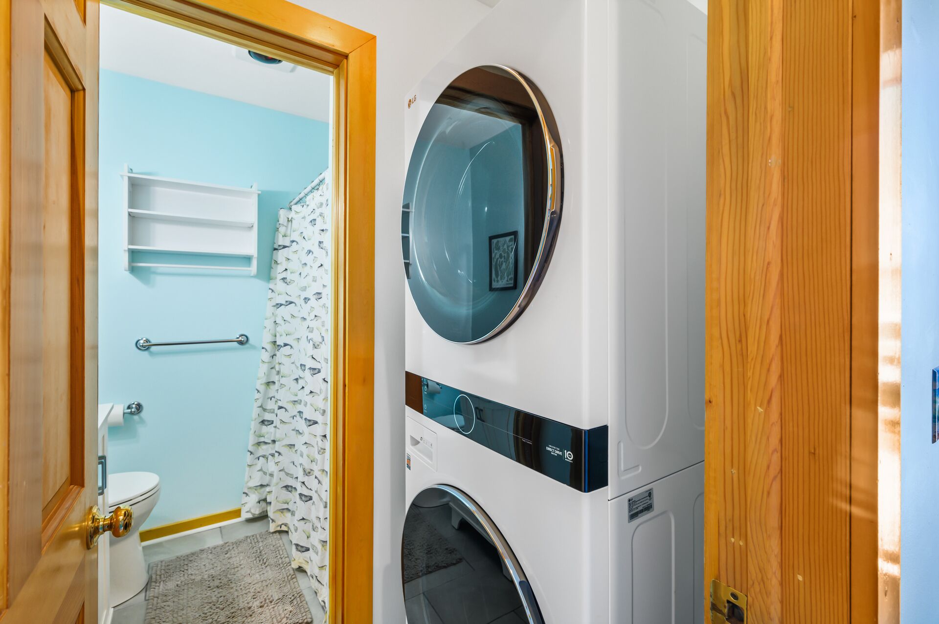 A laundry room with two stacked washing machines, a toilet, and a shower area.