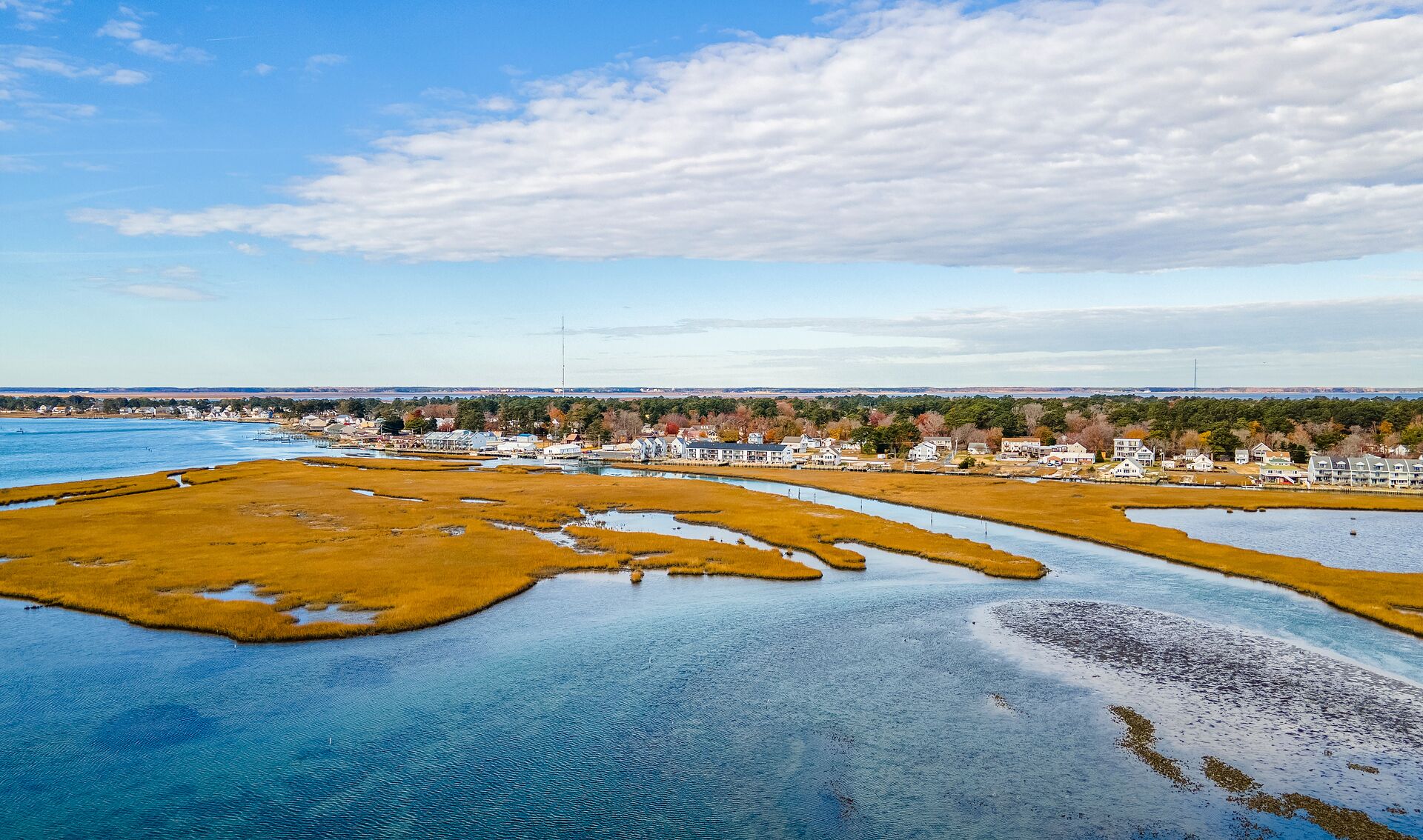 A coastal town with a marina, houses, and a clear sky.