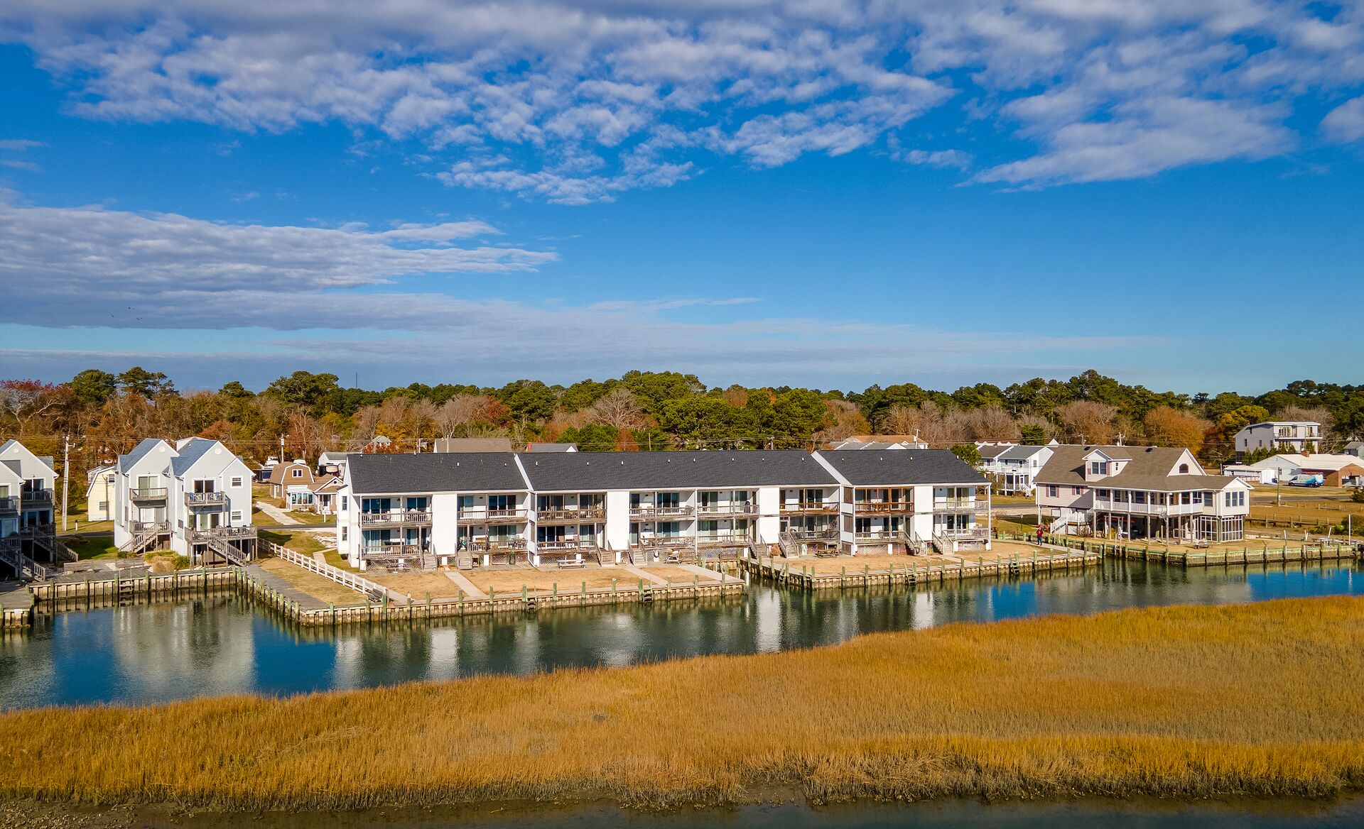A waterfront hotel with multiple-story buildings, a dock, and a grassy area in front.