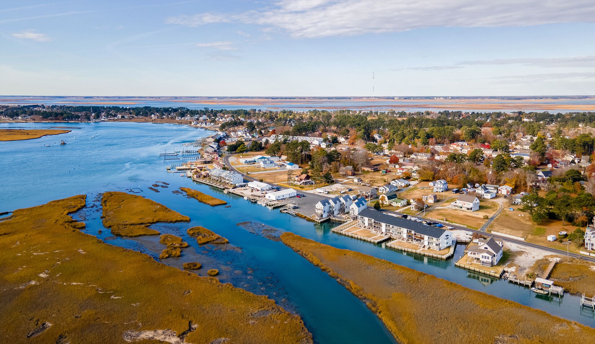 An aerial view of a coastal town with a marina, residential areas, and a river.