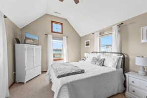 Ein Schlafzimmer mit Bett, Nachttischen, einem Kleiderschrank und einem Fenster mit Vorhängen.
