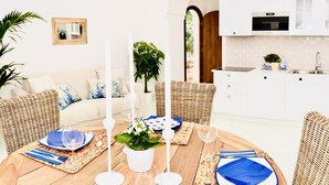 A dining area with a round wooden table set for two, white candles, and a potted plant. - Tyrrhenian Sea View Apartment (Campania)